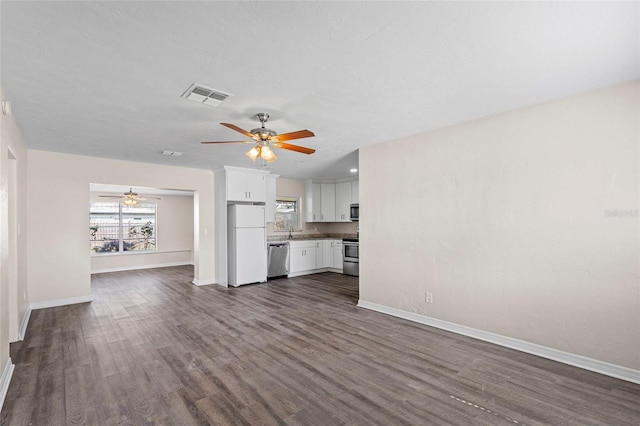 unfurnished living room with ceiling fan, dark hardwood / wood-style flooring, sink, and a wealth of natural light