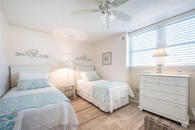 bedroom with ceiling fan, light hardwood / wood-style flooring, and a textured ceiling