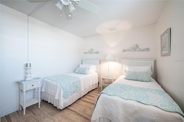 bedroom with ceiling fan, a textured ceiling, and light wood-type flooring