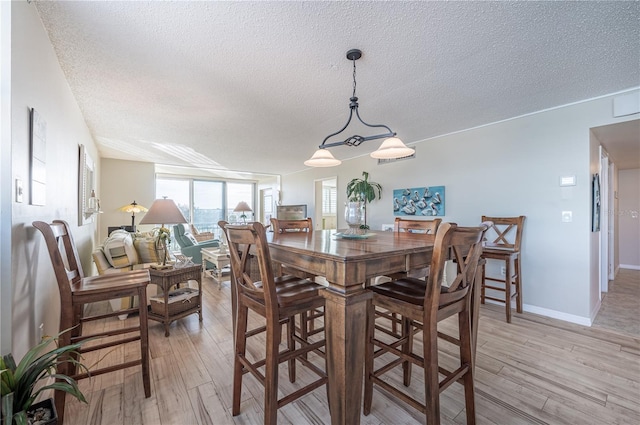 dining room with a textured ceiling and light wood-type flooring