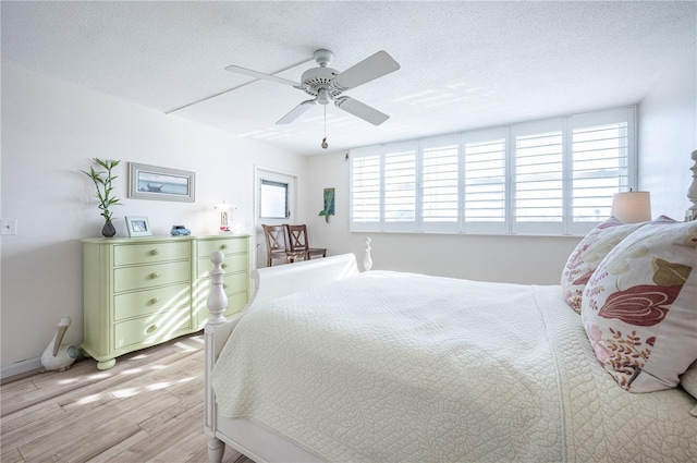 bedroom with ceiling fan, light hardwood / wood-style floors, and a textured ceiling