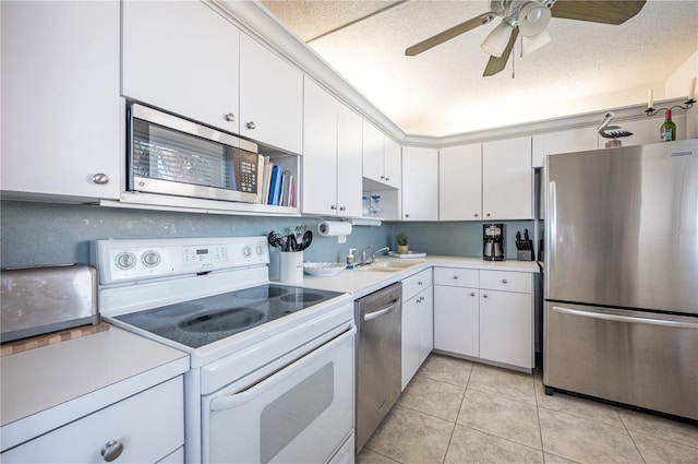 kitchen featuring sink, stainless steel appliances, a textured ceiling, white cabinets, and light tile patterned flooring