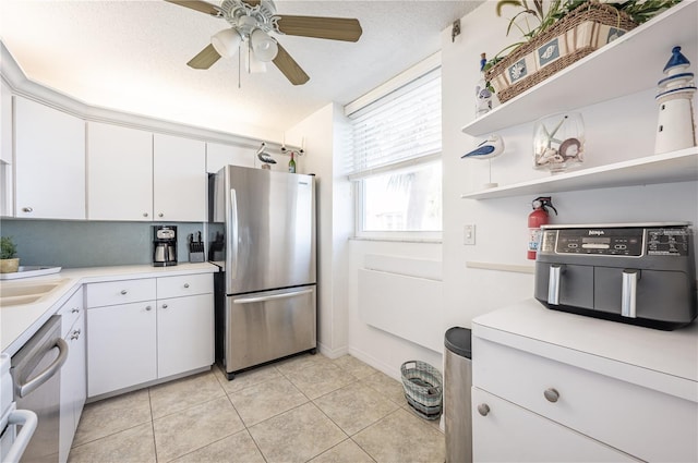 kitchen with appliances with stainless steel finishes, light tile patterned floors, white cabinets, and a textured ceiling