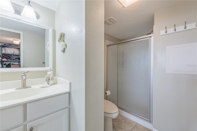 bathroom with vanity, a shower with shower door, tile patterned floors, and toilet