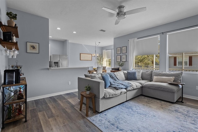 living room featuring ceiling fan with notable chandelier, dark hardwood / wood-style floors, and a textured ceiling