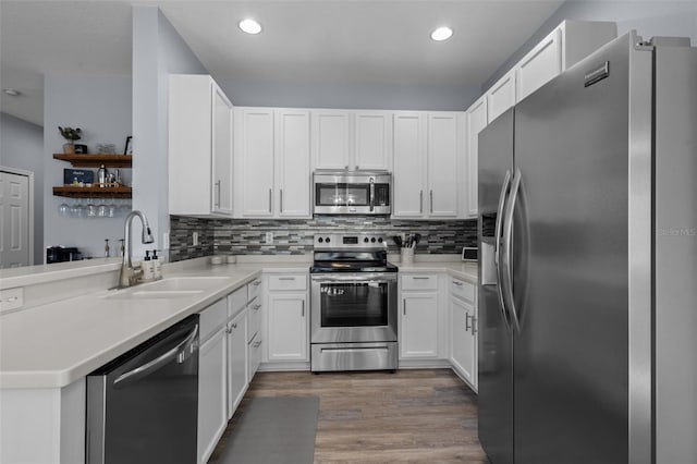 kitchen with white cabinetry, sink, stainless steel appliances, and kitchen peninsula