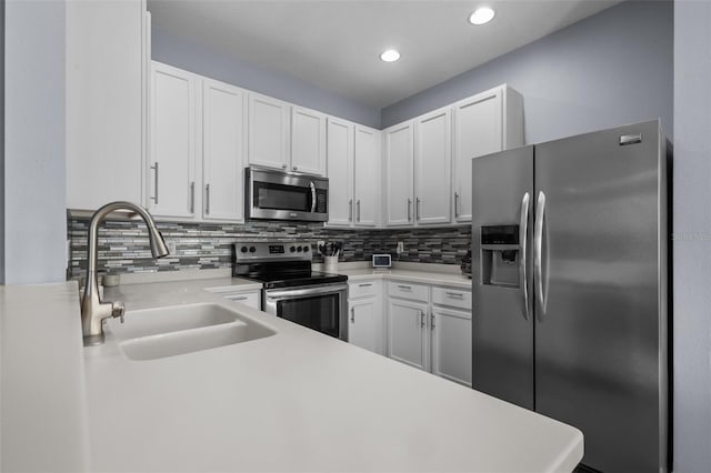 kitchen featuring tasteful backsplash, appliances with stainless steel finishes, sink, and white cabinets