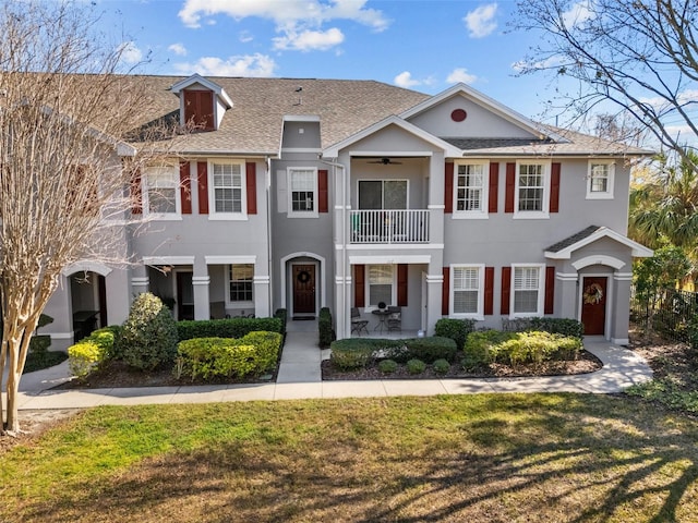 view of front of house with ceiling fan, a front lawn, and a balcony