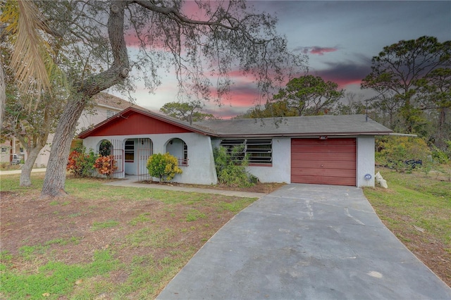 view of front of house with a garage, a front yard, concrete driveway, and stucco siding