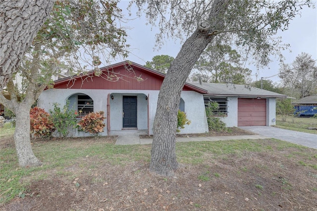 view of front of home with a garage, concrete driveway, a front yard, and stucco siding