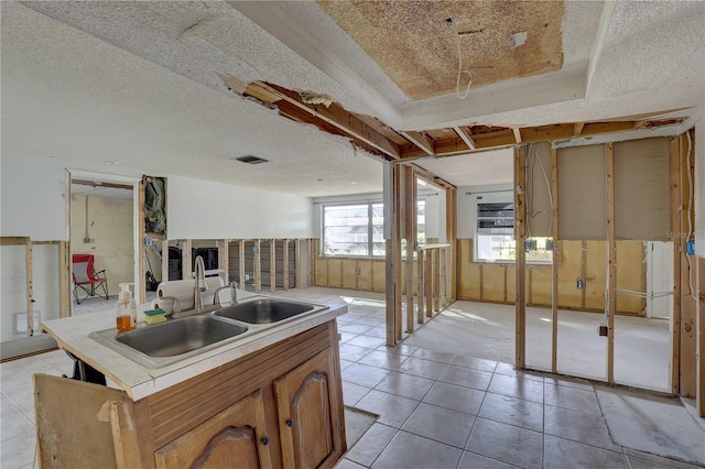 kitchen featuring sink, light tile patterned floors, and a textured ceiling