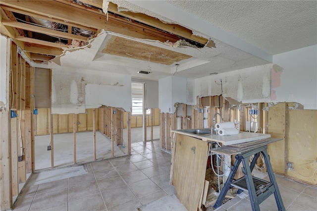 kitchen with light tile patterned flooring, sink, and a textured ceiling