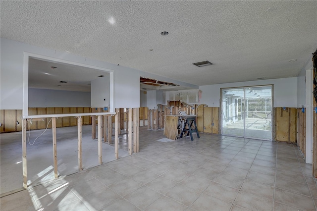 interior space with wooden walls and a textured ceiling