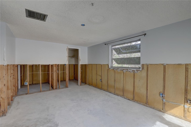 spare room featuring wooden walls and a textured ceiling