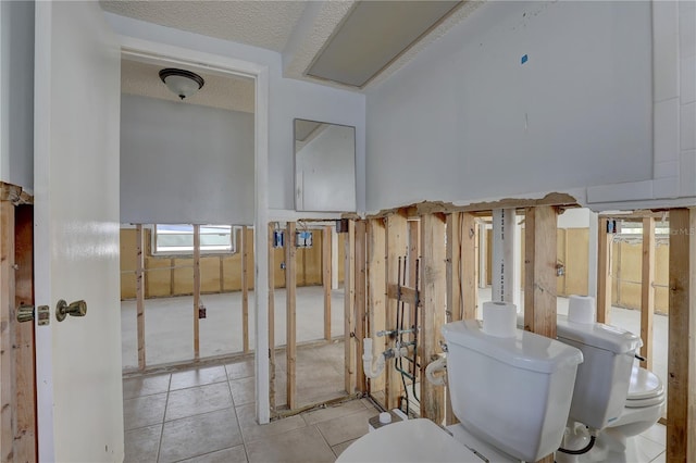 interior space with tile patterned flooring, toilet, and a textured ceiling