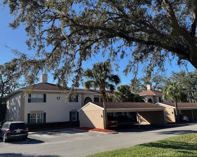 10346 Carrollwood Ln Unit 171, Tampa, FL 33618 - view of front of home with stucco siding, a chimney, and covered parking