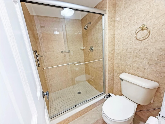 10346 Carrollwood Ln Unit 171, Tampa, FL 33618 - full bathroom featuring tile patterned floors, toilet, tile walls, and a stall shower