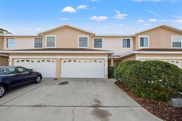 view of property featuring driveway, an attached garage, and stucco siding