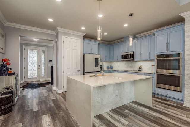 kitchen featuring stainless steel appliances, a kitchen island with sink, dark wood-type flooring, and decorative light fixtures