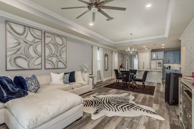 living room with sink, ornamental molding, a tray ceiling, dark hardwood / wood-style flooring, and ceiling fan with notable chandelier