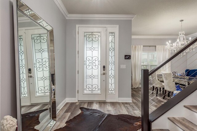 foyer featuring hardwood / wood-style flooring, ornamental molding, and a chandelier