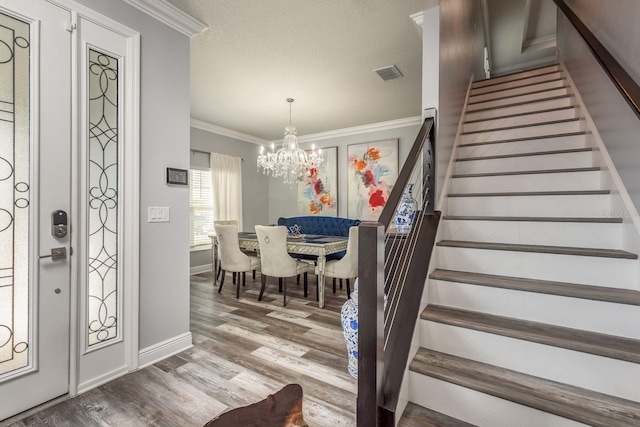 entrance foyer with ornamental molding, wood-type flooring, and a chandelier