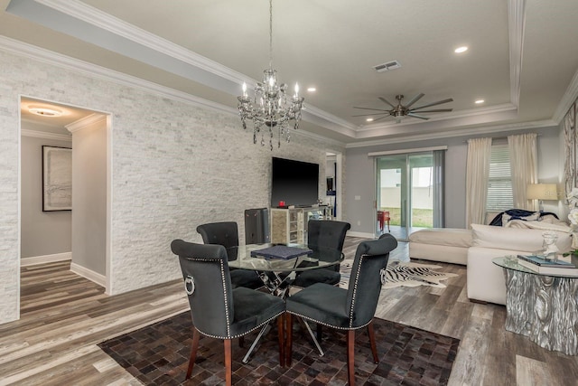 dining area featuring crown molding, ceiling fan with notable chandelier, hardwood / wood-style floors, and a tray ceiling