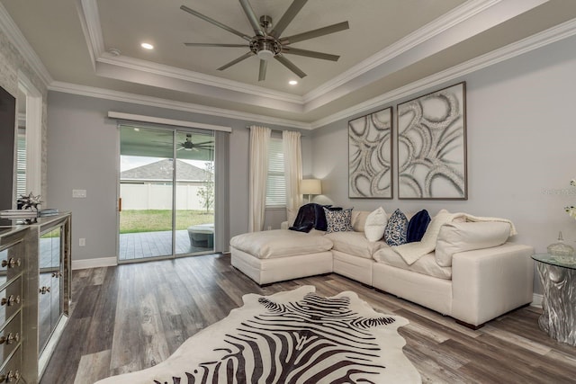 living room with hardwood / wood-style floors, ornamental molding, and a raised ceiling