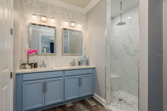 bathroom featuring hardwood / wood-style flooring, ornamental molding, tiled shower, and vanity