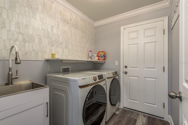 clothes washing area featuring sink, crown molding, dark hardwood / wood-style floors, washer and dryer, and a textured ceiling