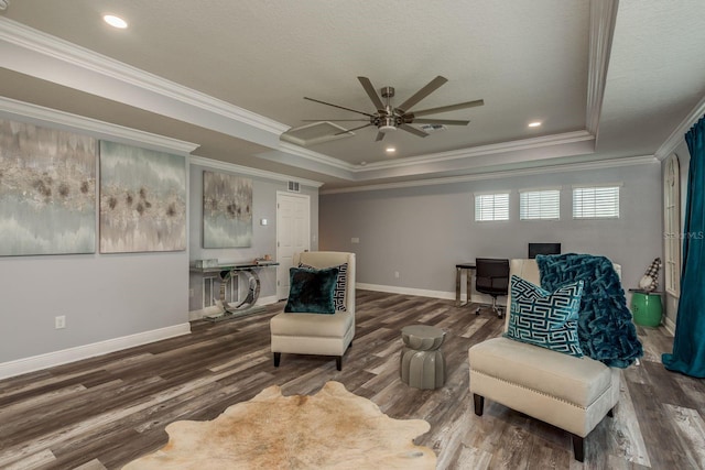 living area with a textured ceiling, ornamental molding, a raised ceiling, hardwood / wood-style flooring, and ceiling fan