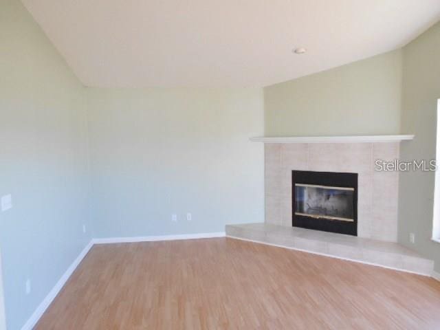 unfurnished living room featuring a tiled fireplace and light hardwood / wood-style floors