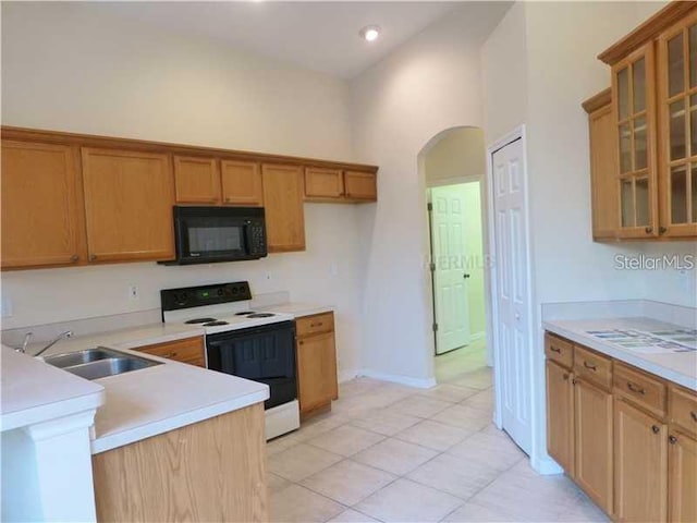 kitchen featuring a towering ceiling, sink, light tile patterned floors, and white range with electric cooktop