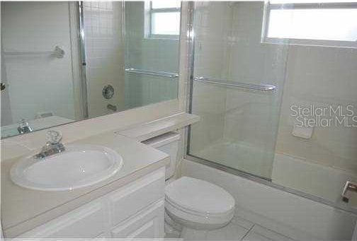 full bathroom with enclosed tub / shower combo, a wealth of natural light, vanity, and toilet