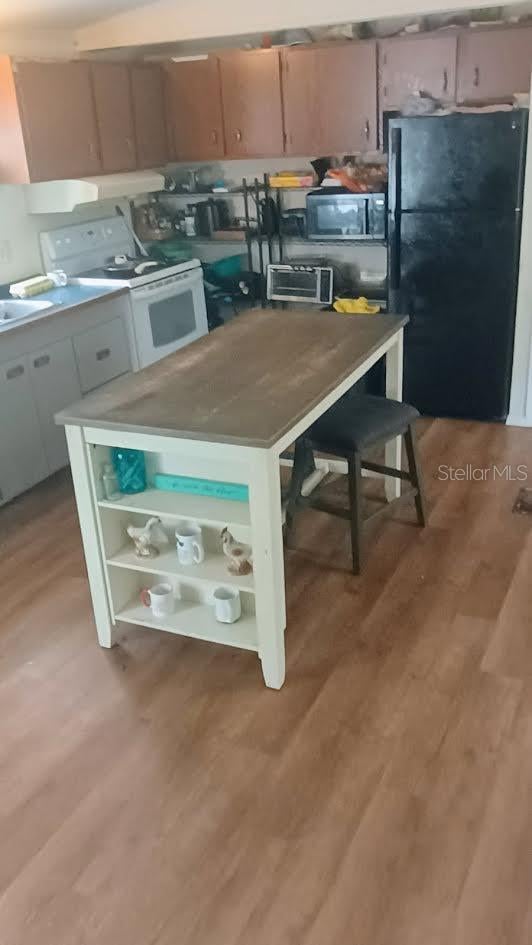 kitchen with black refrigerator, light hardwood / wood-style flooring, and white range with electric cooktop