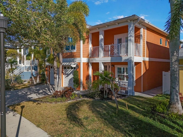 view of front facade featuring a balcony, a garage, and a front lawn