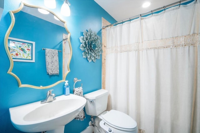 bathroom with a shower with shower curtain, toilet, and sink