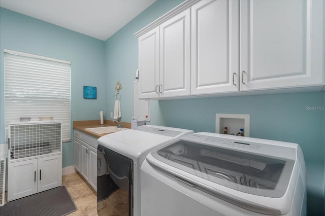 laundry room with cabinets, washing machine and dryer, and sink