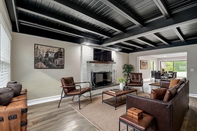 living room featuring wood ceiling, beam ceiling, hardwood / wood-style floors, and a brick fireplace