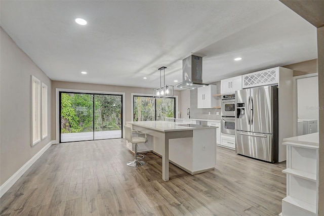 kitchen featuring pendant lighting, light hardwood / wood-style flooring, white cabinetry, stainless steel appliances, and island exhaust hood