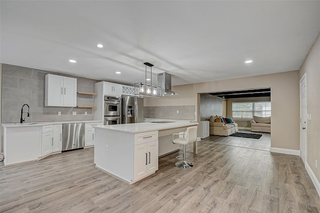 kitchen with decorative light fixtures, a kitchen island, white cabinets, and appliances with stainless steel finishes