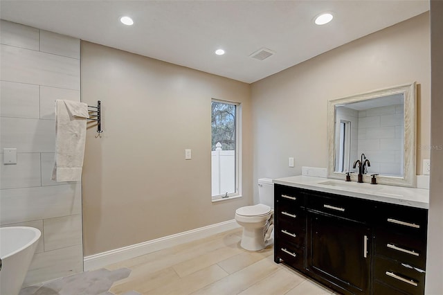 bathroom with hardwood / wood-style flooring, vanity, toilet, and a tub