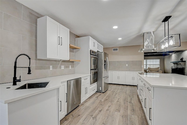 kitchen featuring appliances with stainless steel finishes, tasteful backsplash, sink, white cabinets, and hanging light fixtures