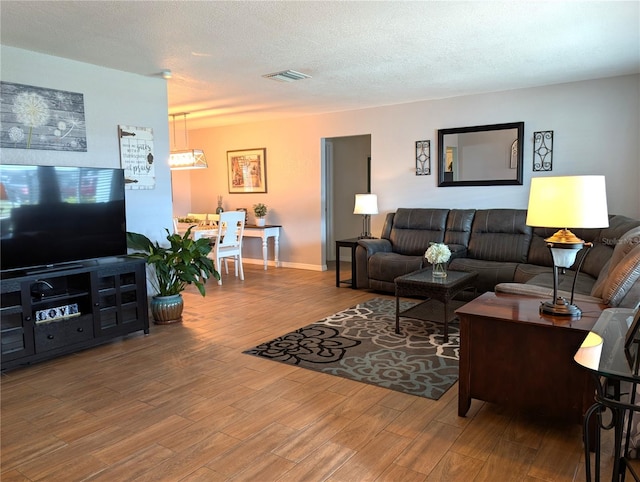 living area featuring a textured ceiling, baseboards, and wood finished floors