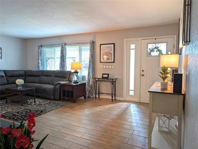 living room with baseboards, a textured ceiling, and light wood-style floors