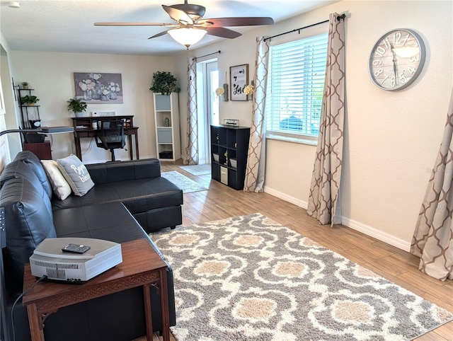 living area featuring baseboards, ceiling fan, and wood finished floors