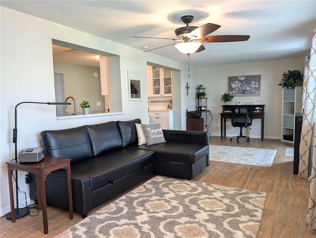 living room featuring baseboards, ceiling fan, and wood finished floors