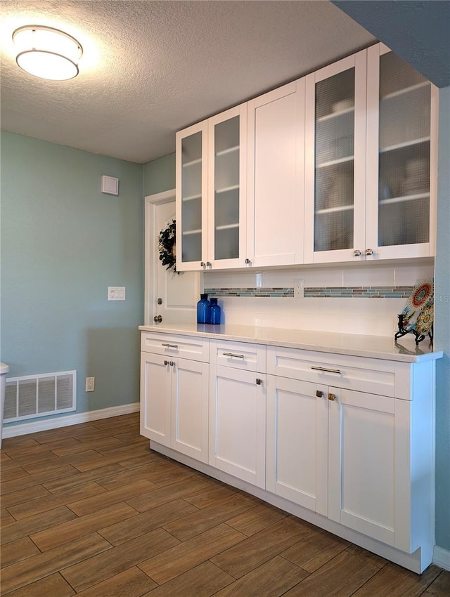 kitchen with light countertops, white cabinets, visible vents, and dark wood-style flooring