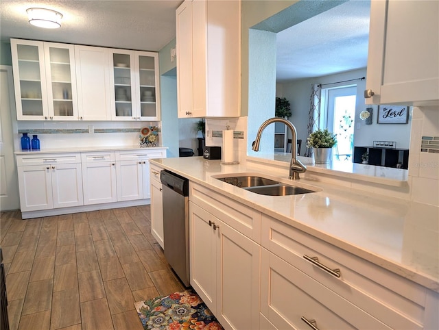 kitchen featuring wood finished floors, a sink, light countertops, white cabinets, and stainless steel dishwasher