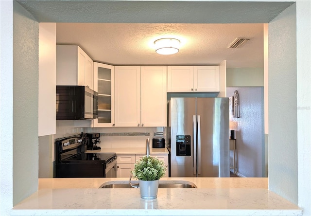 kitchen with light stone counters, visible vents, stainless steel appliances, glass insert cabinets, and white cabinetry